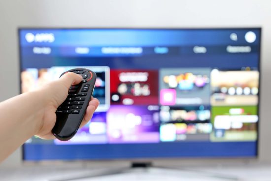 Female hand with remote controller on smart TV