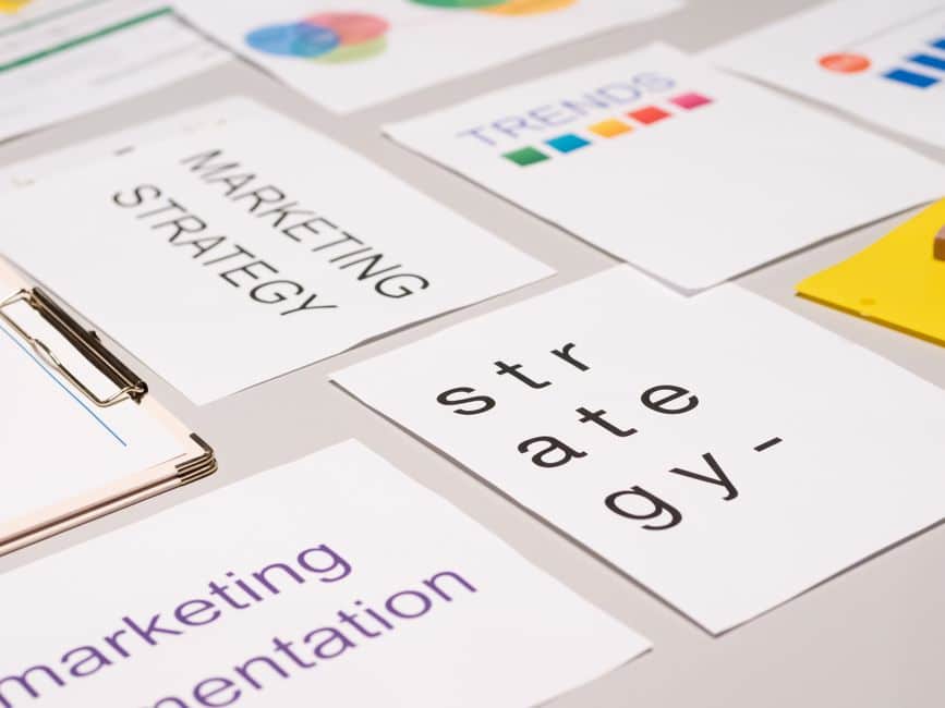 Notes on a white desk showing marketing strategy, presentation, and trends cards laid out clearly on the surface.
