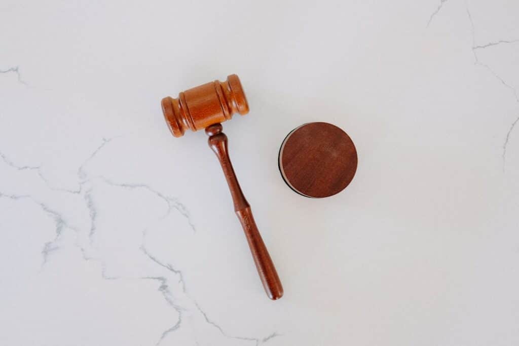 Wooden judge's gavel with a round sound block on a light marble surface